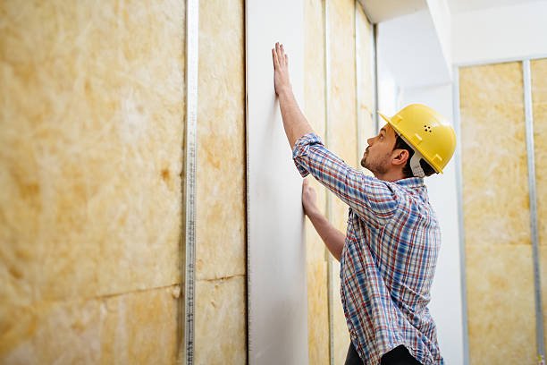 Construction worker on construction site building up a drywall.